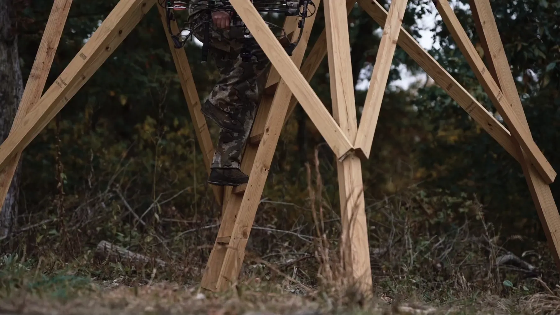 Bowhunter climbing into an elevated NXTGen blind before dawn